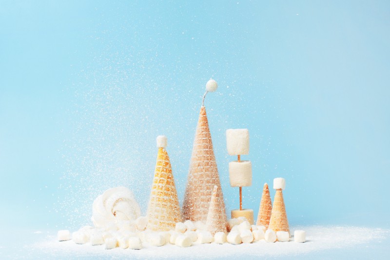 Conceptual photo of upside-down ice cream cones dusted with white powder against a light blue backdrop