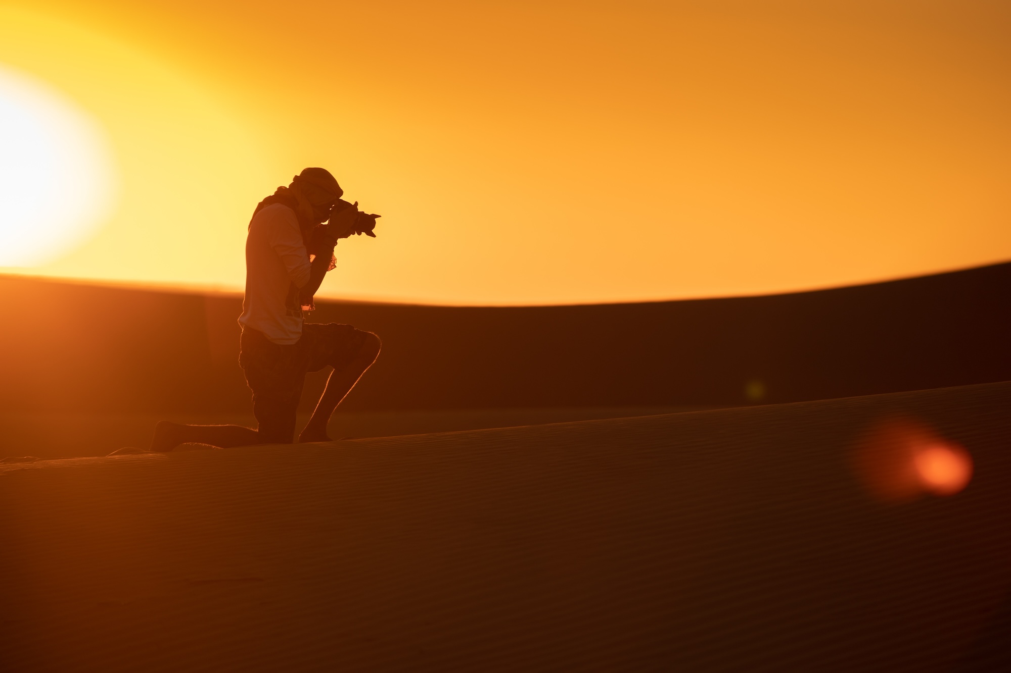 A man takes a photo in the desert. Create Marketable Photography Style with Tools Like VSCO to Increase Your Chances of Getting Hired for as a Photographer