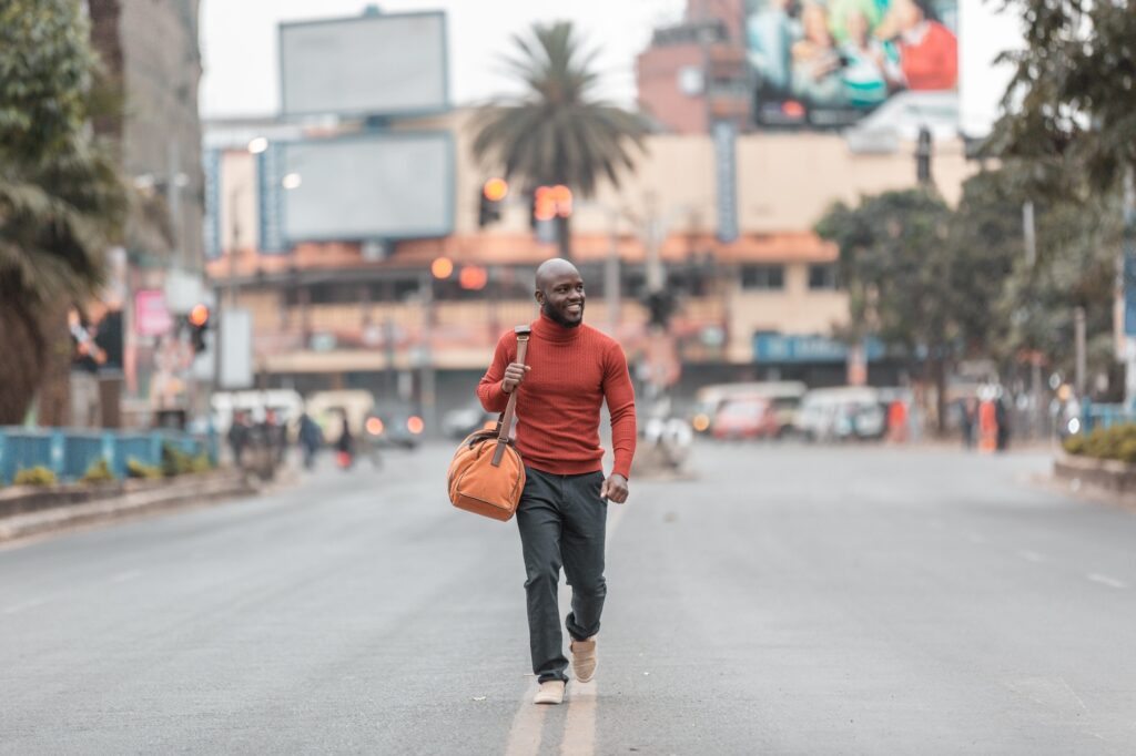A photo of a man walking down the street with a duffel bag that could show brands what it's like to work with a photographer who shoots fashion or lifestyle products.